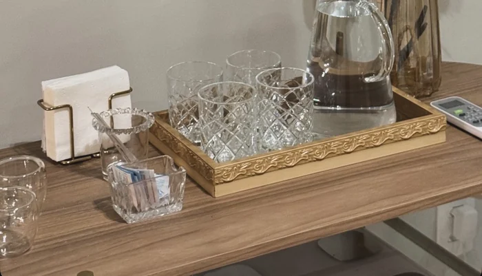 Detalhe do consultório: aparador de boas-vindas com água, cristais e flores.